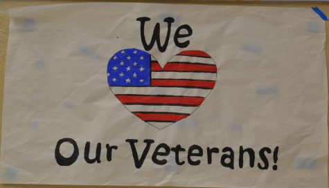 A poster thanking veterans hangs in the school hallway.