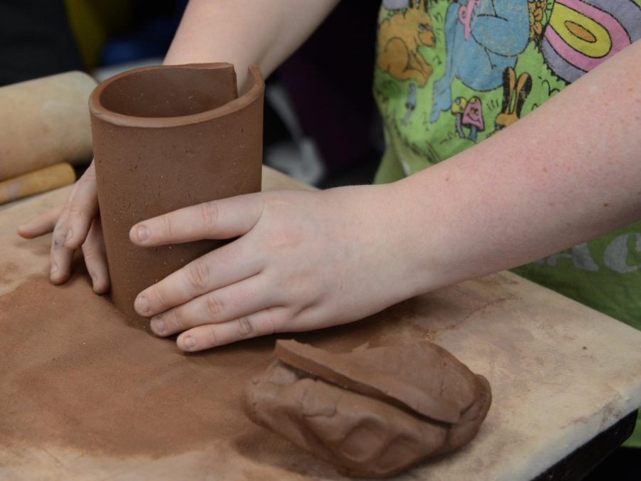 Pottery student folding her mug together