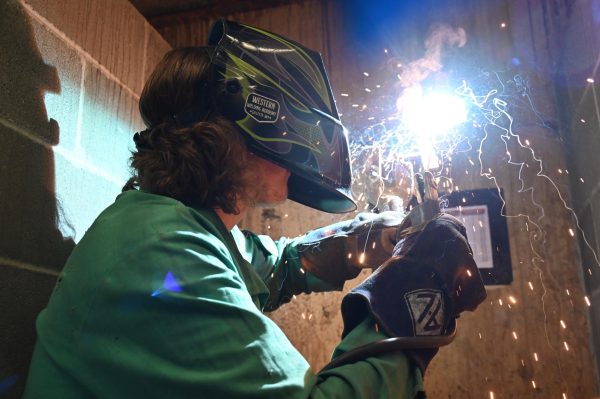 Gage Oles welds his metal together with a rod 